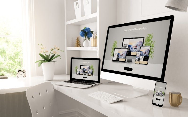 Modern workspace showing a responsive website design displayed across desktop, laptop, and mobile screens